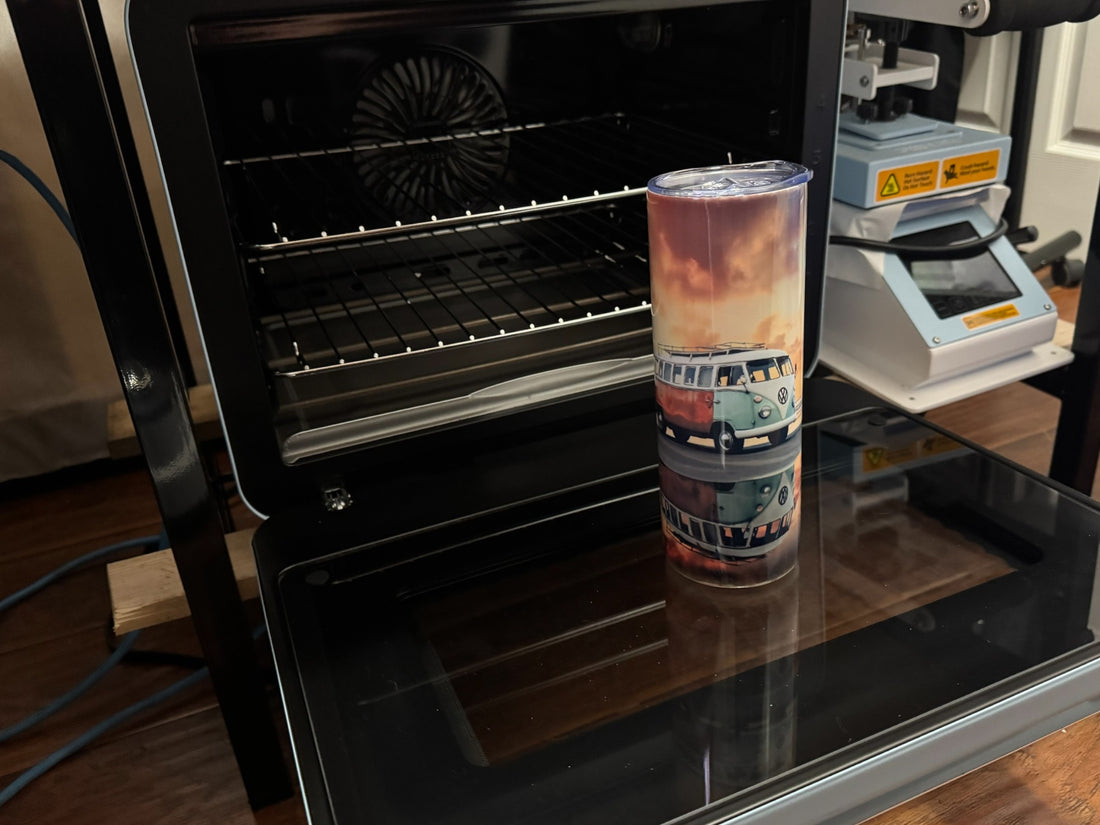 A sublimation tumbler with a vibrant design of a vintage van placed on top of a sublimation oven, with a heat press machine visible in the background.