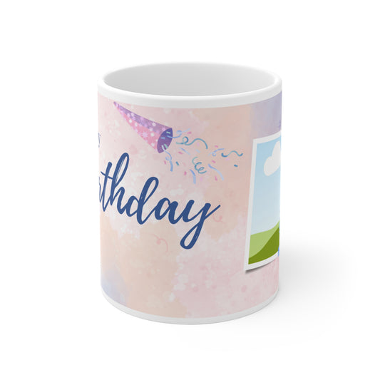 A white ceramic mug featuring a festive "Happy Birthday" design. The background is a soft pastel pink with watercolor-style splashes and subtle confetti accents. Above the "Happy Birthday" text in elegant blue script, there are colorful bunting flags in shades of pink, purple, and blue, adding a cheerful and celebratory touch to the mug's design.