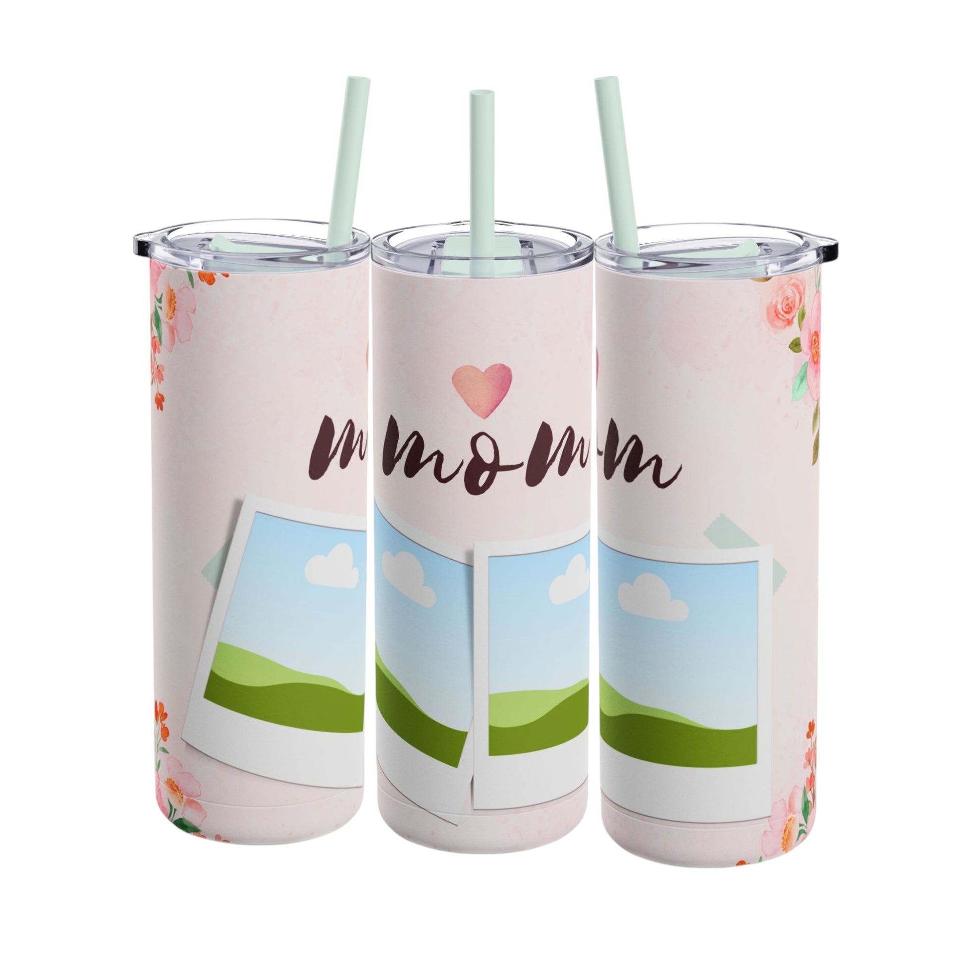 A set of three stainless steel tumblers with reusable straws and clear lids. The design features a soft pink background adorned with delicate floral accents in shades of pink and orange. The center tumbler displays the word "mom" in elegant script with a heart above it. Each tumbler includes placeholders for family photos, framed against a scenic backdrop of green hills, blue skies, and white clouds, creating a heartfelt and personalized theme perfect for moms.