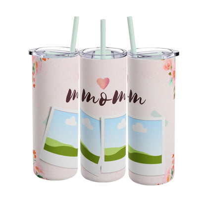 A set of three stainless steel tumblers with reusable straws and clear lids. The design features a soft pink background adorned with delicate floral accents in shades of pink and orange. The center tumbler displays the word "mom" in elegant script with a heart above it. Each tumbler includes placeholders for family photos, framed against a scenic backdrop of green hills, blue skies, and white clouds, creating a heartfelt and personalized theme perfect for moms.