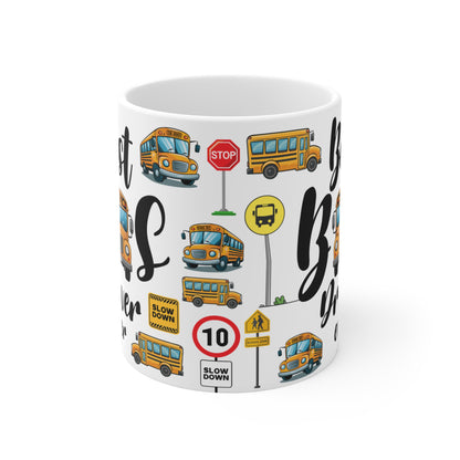 A white ceramic mug featuring a vibrant, colorful school bus-themed design. The design includes illustrations of yellow school buses, stop signs, slow down signs, and road symbols like speed limit signs and pedestrian crossing signs, all arranged in a playful and repeating pattern. The text "Slow Down" and "Stop" is visible on some of the signs.